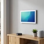 Matte black smart home hub and smart speaker on an oak console table below a wall-mounted smart home touchscreen in a modern American home