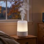 White smart humidifier releasing mist on a nightstand and a black humidifier on a dresser in a cozy American bedroom in fall