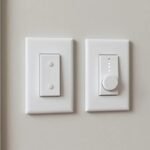 Two white smart light switches, a paddle switch and a dimmer, on a wall in a modern American home entryway